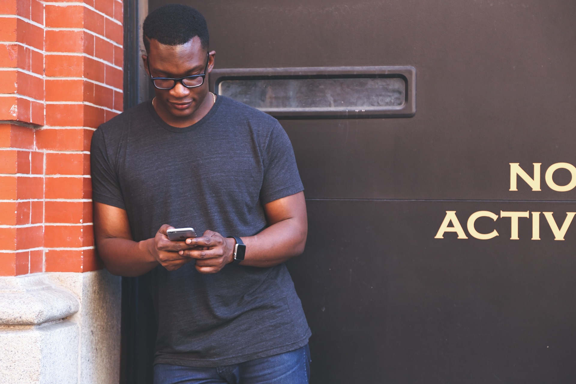 Man using mobile phone leaning against a building