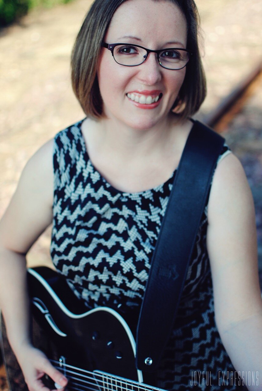 Becky Boyland playing guitar and looking up